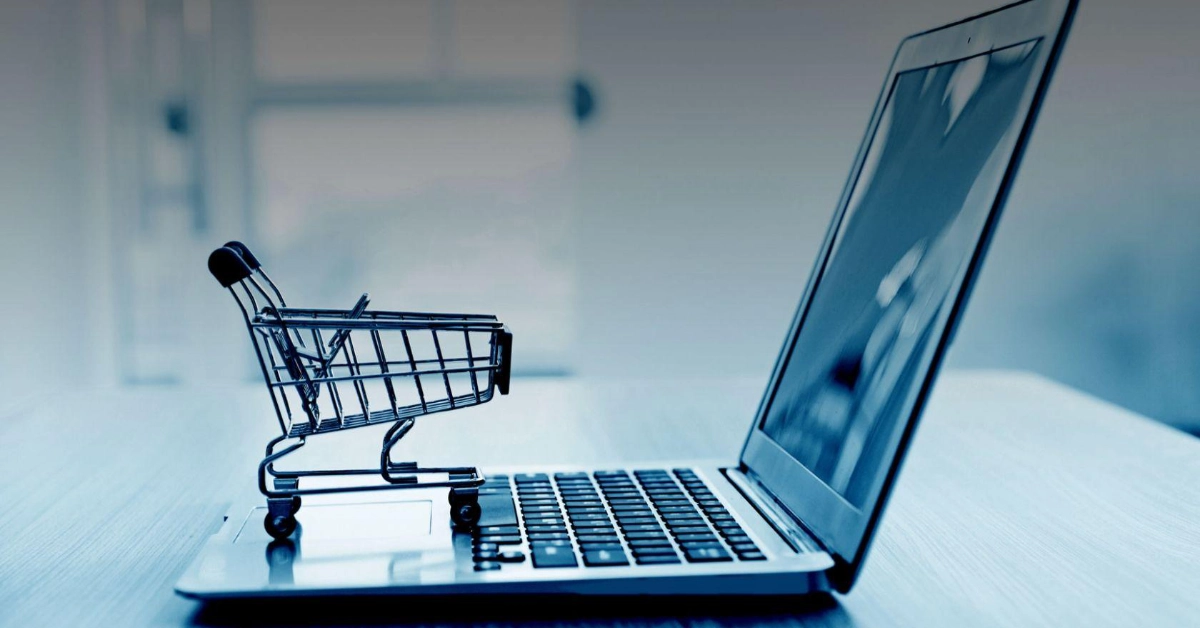 Small shopping trolley on a laptop keyboard representing online shopping, ecommerce, and digital purchasing